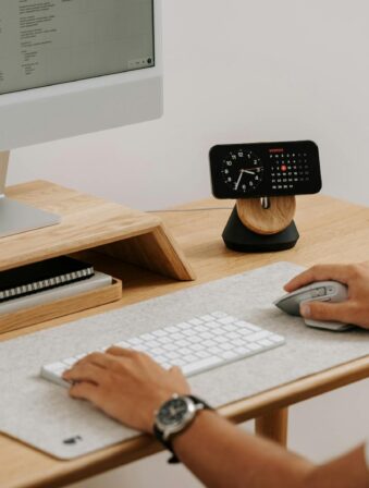 A clean and modern desk setup featuring a computer, clock, and accessories in a home office.